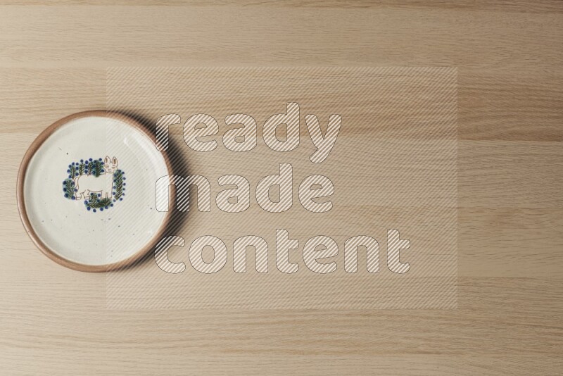 A decorative pottery plate on light wooden background