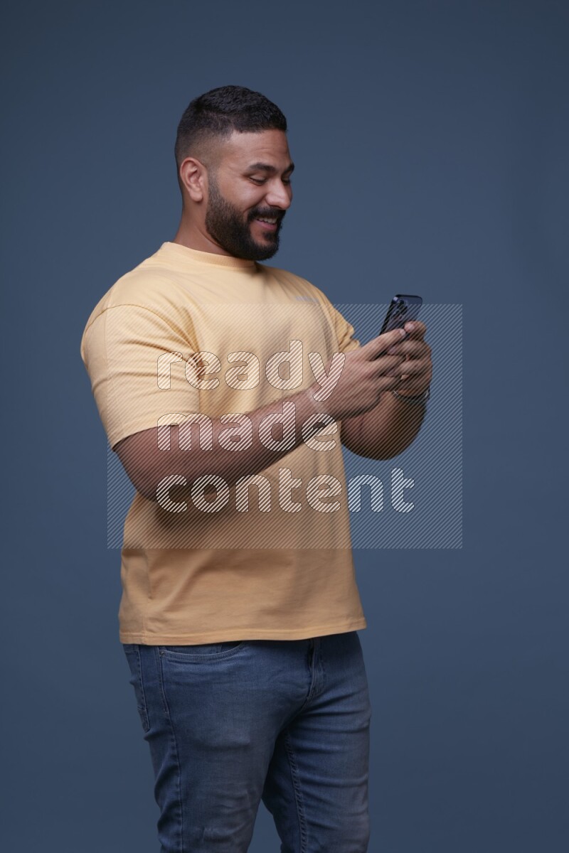 A man Texting on his phone in Blue Background wearing Orange T-shirt