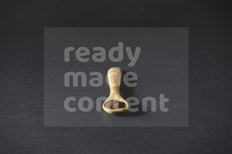 بودرة القرنفل في ملعقة خشبية علي خلفية سوداء