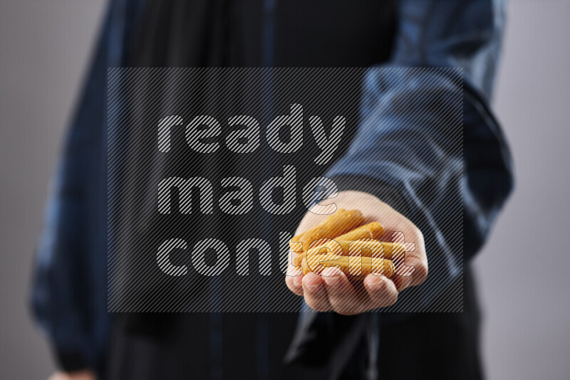 Woman in abaya holding different kinds of snacks in different positions