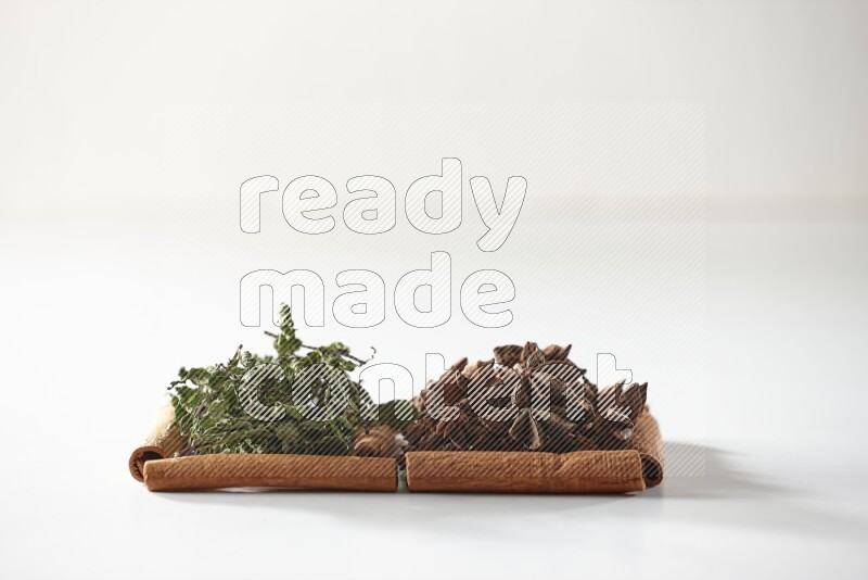 2 squares of cinnamon sticks full of star anise and dried mint leaves on white flooring