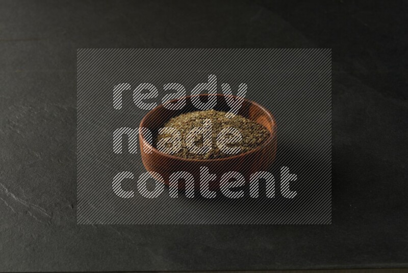 wooden round sauce bowl filled with herbs on grey textured countertop