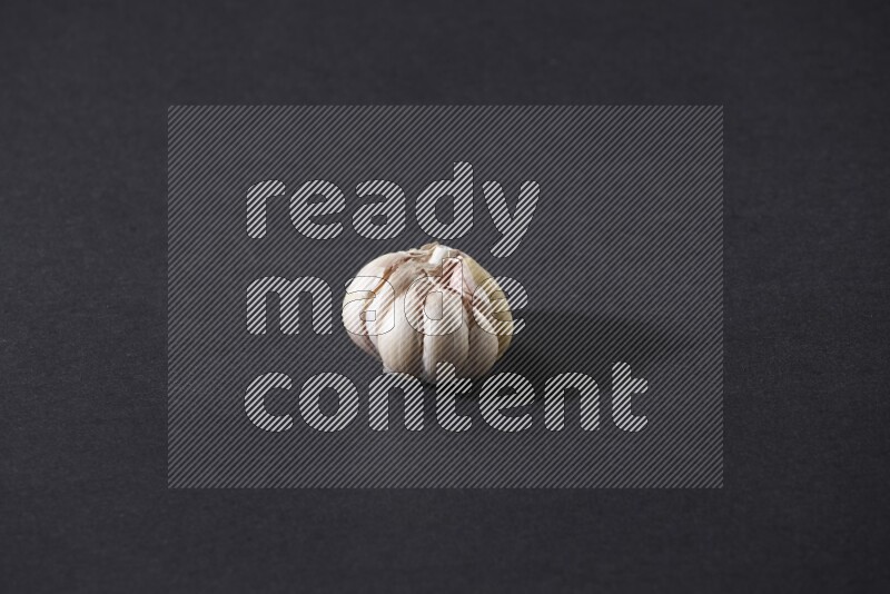 A whole garlic bulb placed on a black flooring