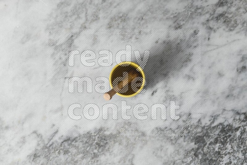 Multicolored pottery cup with wooden honey dipper in it on grey marble background