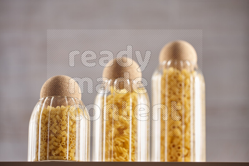 Raw pasta in glass jars on beige background
