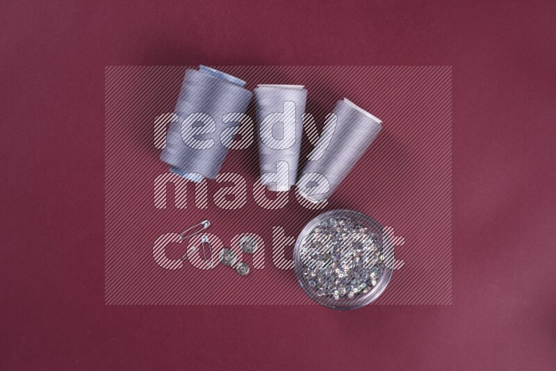 مجموعة من أدوات الخياطة والتفصيل رمادية اللون على خلفية حمراء