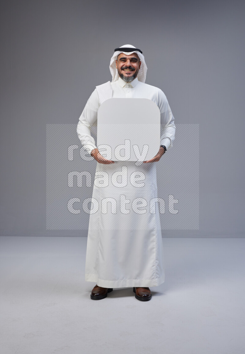 Saudi man Wearing Thob and white Shomag standing holding social media sign on Gray background