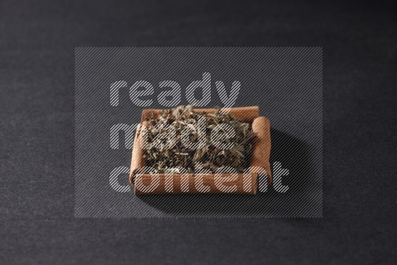 A single square of cinnamon sticks full of dried basil on black flooring