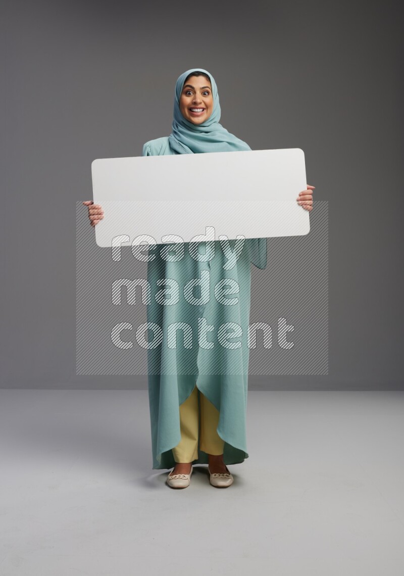 Saudi Woman wearing Abaya standing holding board on Gray background