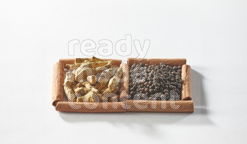 2 squares of cinnamon sticks full of black peppers and turmeric fingers on white flooring