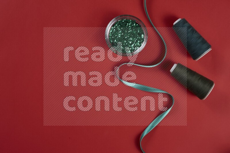 A green and red collection of sewing and tailoring tools arranged on a red background
