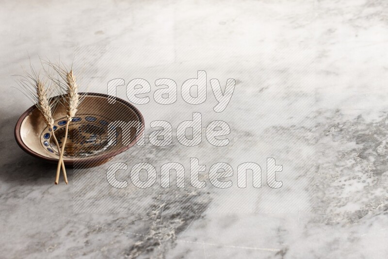Wheat stalks on decorative pottery plate on grey marble background