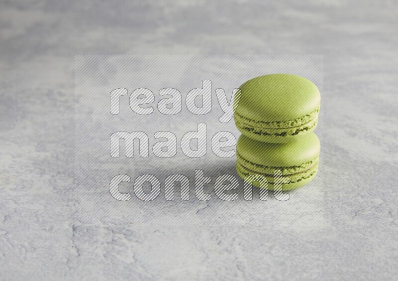 45º Shot of two Green Pistachio macarons  on white  marble background