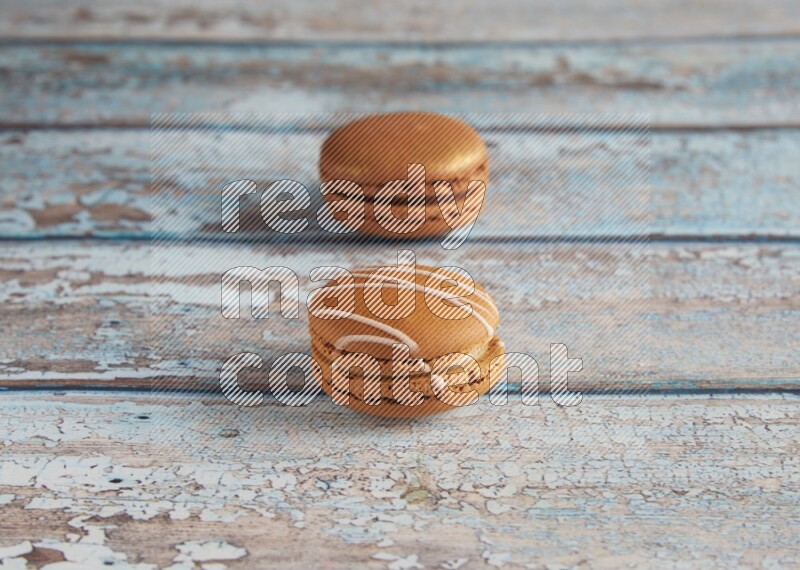 45º Shot of of two assorted Brown Irish Cream, and Brown Coffee macarons on light blue background