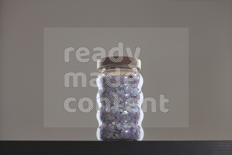 Sequins in a glass jar on black background