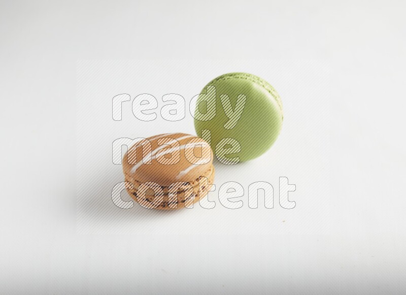 45º Shot of of two assorted Brown Irish Cream, and Green Pistachio macarons on white background