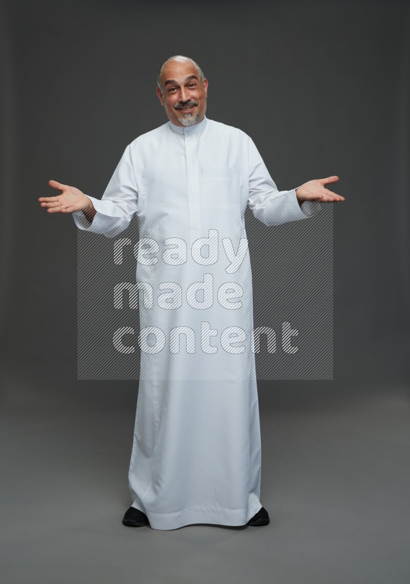 Saudi man without shomag Standing Interacting with the camera on gray background