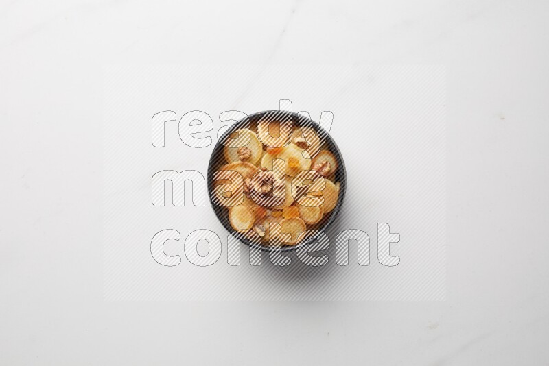Top-view shot of walnut and apricot cereal pancakes in a round bowl on white background