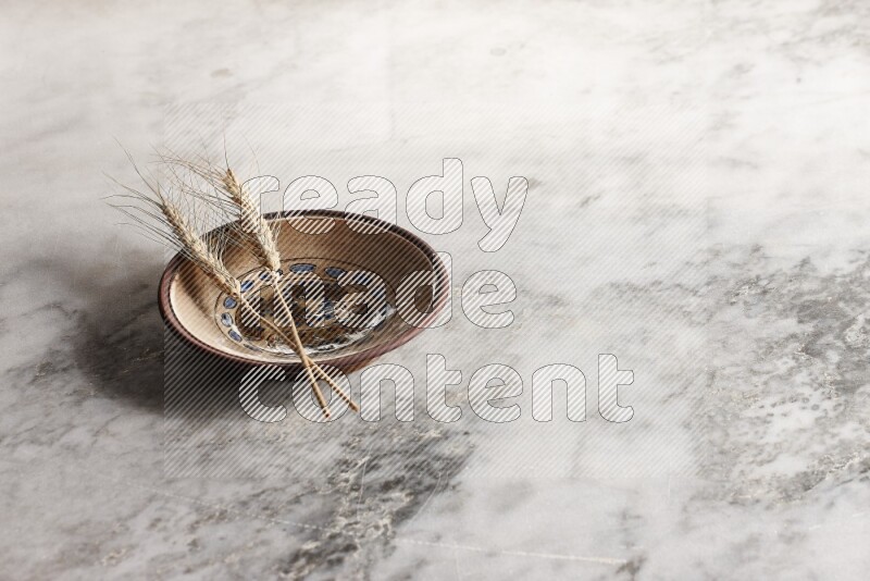 Wheat stalks on decorative pottery plate on grey marble background