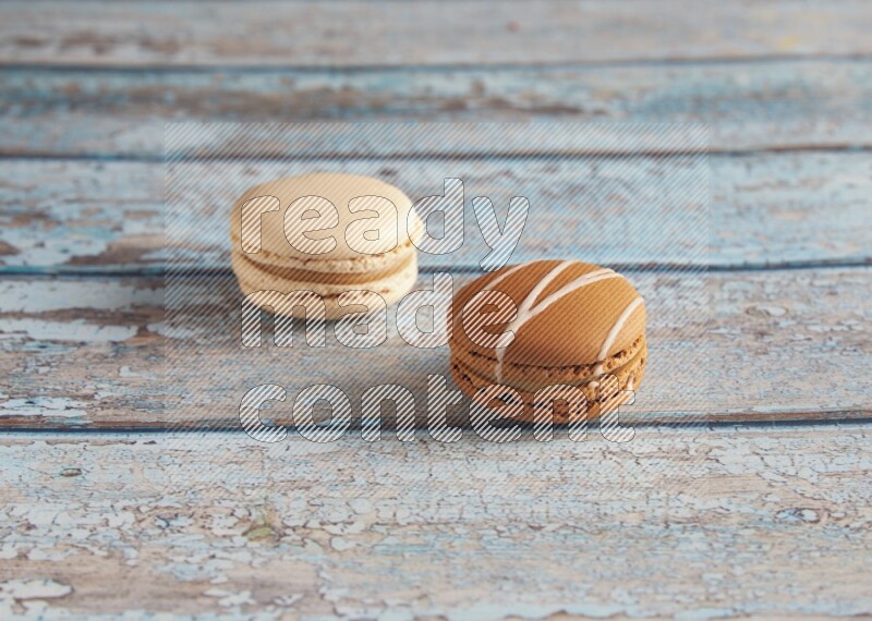 45º Shot of of two assorted Brown Irish Cream, and White Caramel fleur de sel macarons on light blue background