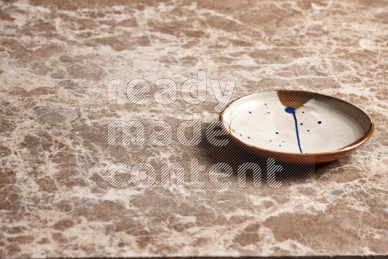 A multicolored pottery plate on beige marble background