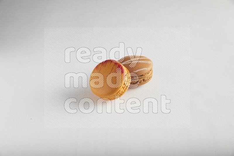 45º Shot of of two assorted Brown Irish Cream, and Orange Exotic macarons on white background