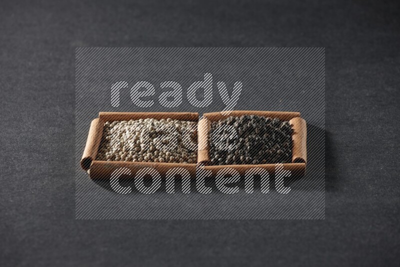 2 squares of cinnamon sticks full of white peppers and black peppers on black flooring