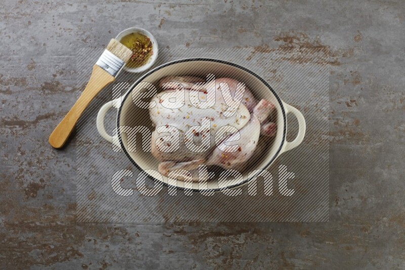 whole raw chicken on in a white ceramic pot direct on a rustic grey background