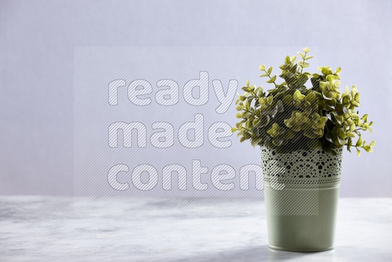 Artificial plant in green decorative pot on grey marble background