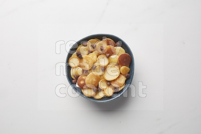 Top-view shot of chocolate chips cereal pancakes in a round bowl on white background