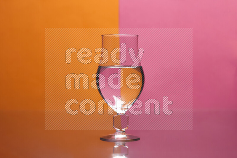 The image features a clear glassware filled with water, set against orange and pink background