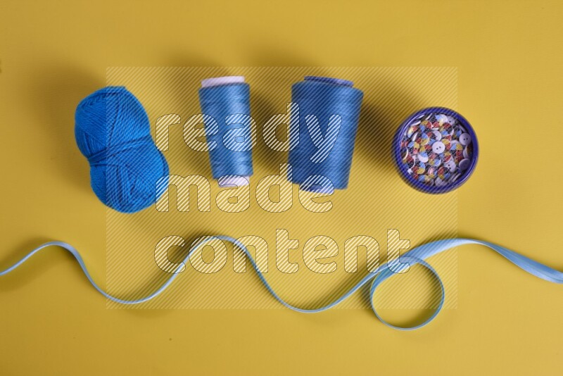 A blue collection of sewing and tailoring tools arranged on a yellow background