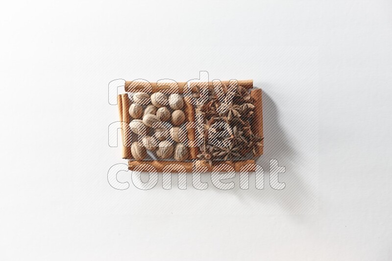 مربعان من أعواد القرفة ممتلئان باليانسون النجمي وجوزة الطيب علي خلفية بيضاء