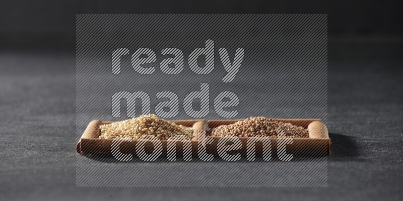 مربعان من أعواد القرفة ممتلئان بحبوب الخردل وبذور السمسم علي خلفية سوداء