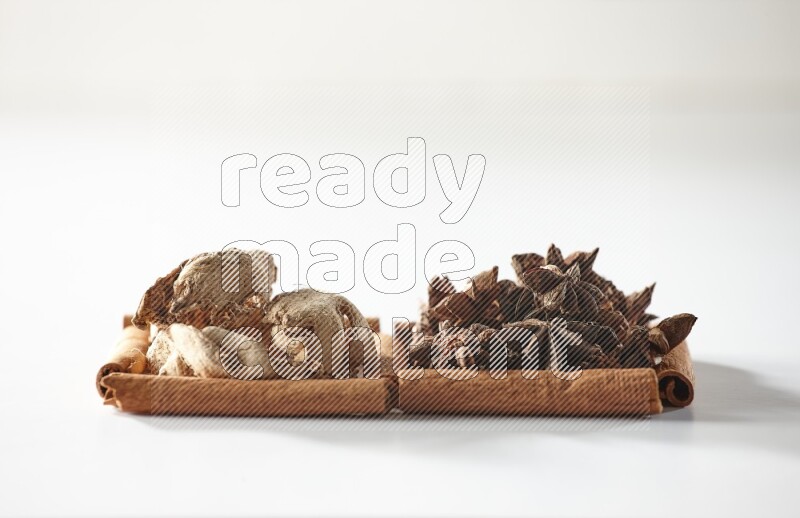 2 squares of cinnamon sticks full of star anise and dried ginger on white flooring