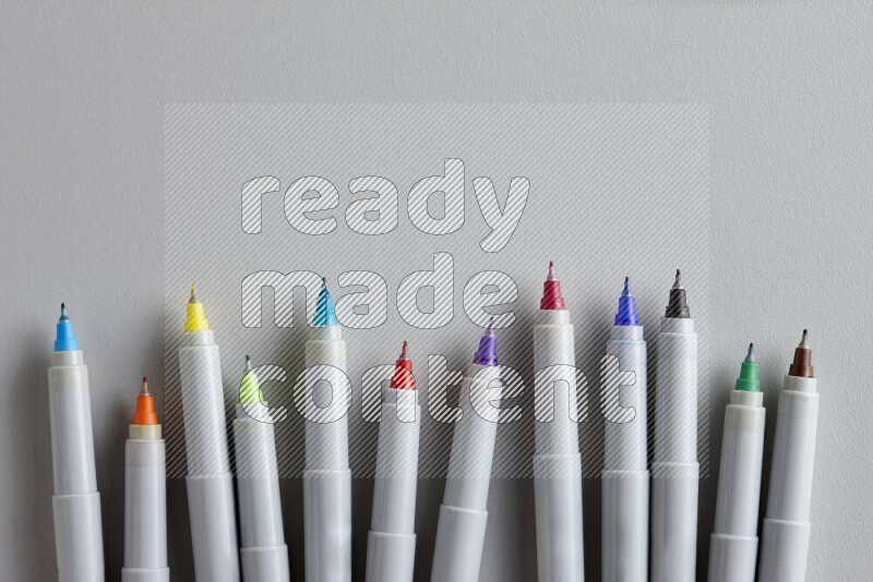 An arrangement of coloring pens in different colors on grey background
