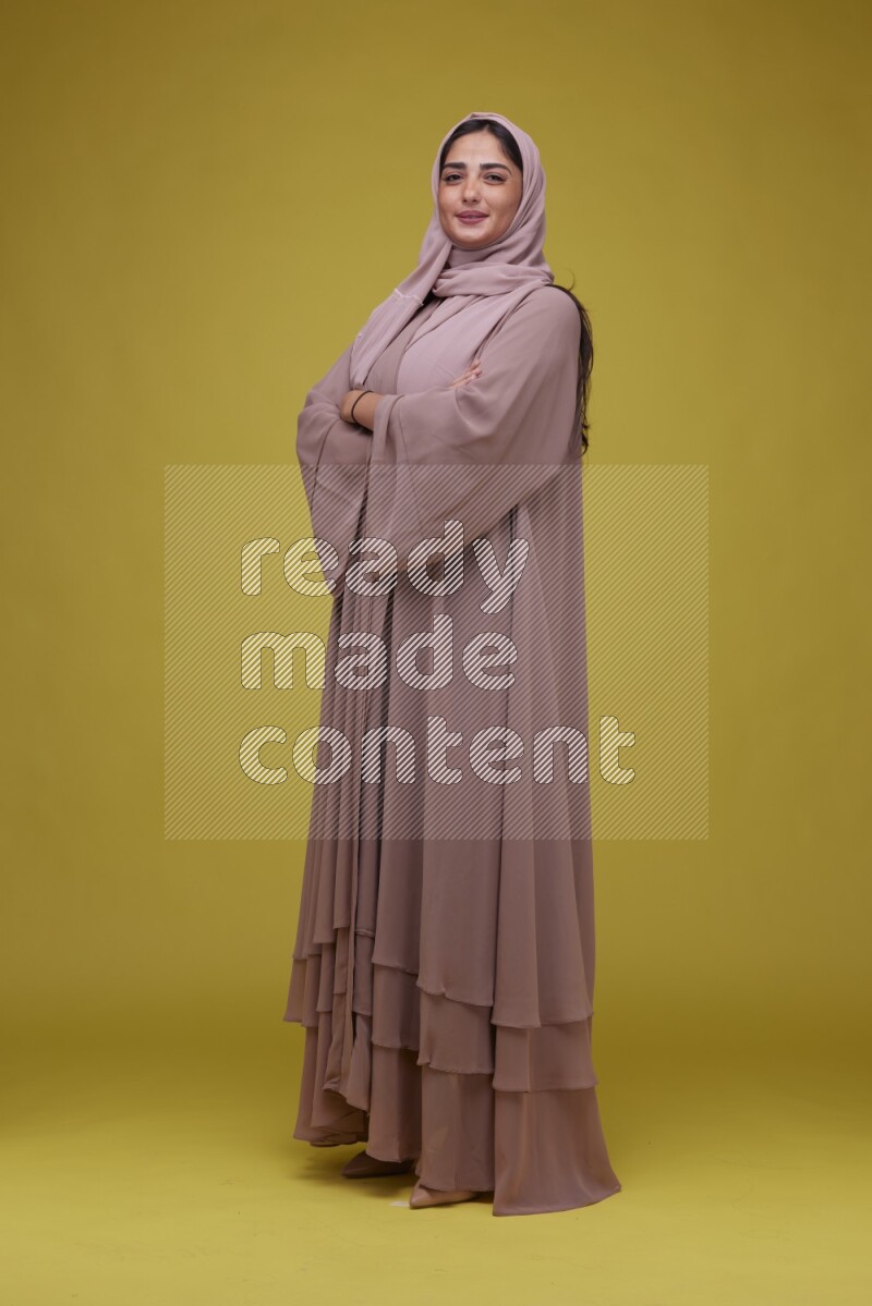 A woman Posing on a Yellow Background wearing Brown Abaya with Hijab