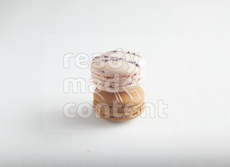 45º Shot of of two assorted Brown Irish Cream, and pink orange blossom macarons on white background