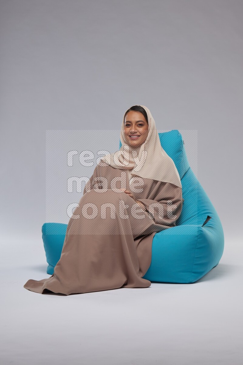 A woman sitting on a blue beanbag and interacting with the camera