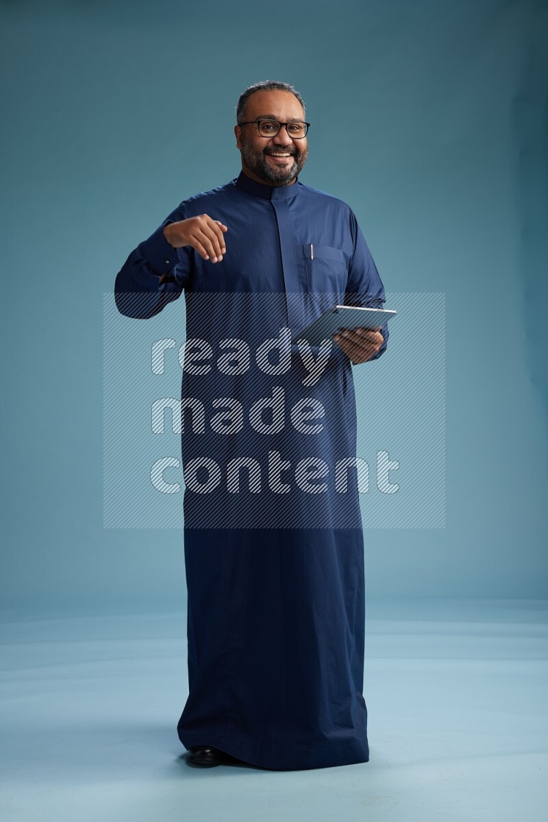 Saudi Man without shimag Standing working on tablet on blue background