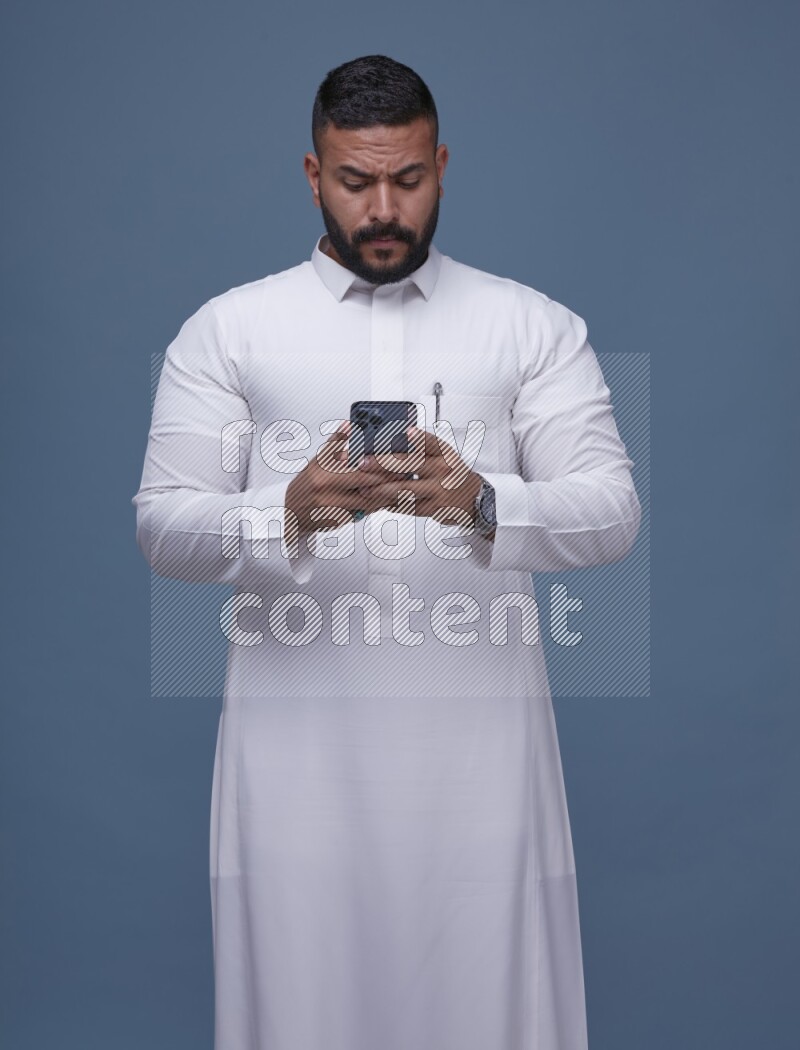 A man Texting on Blue Background wearing Saudi Thob