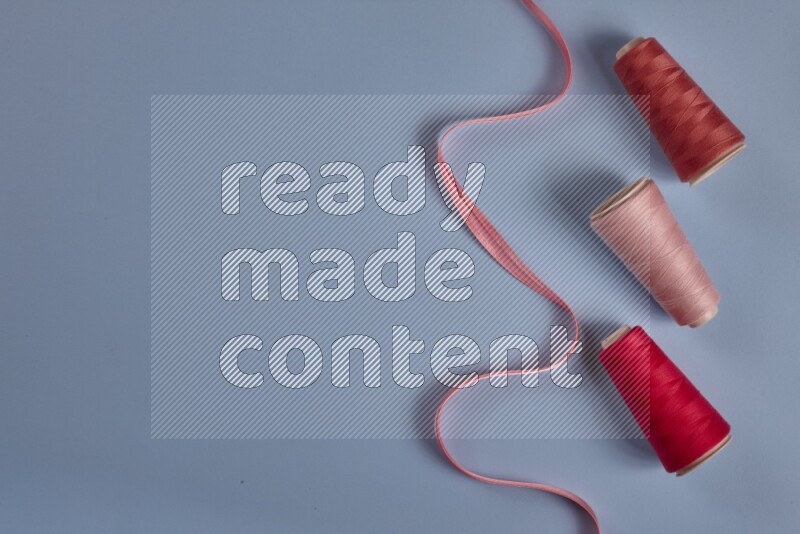 A pink collection of sewing and tailoring tools arranged on a blue background