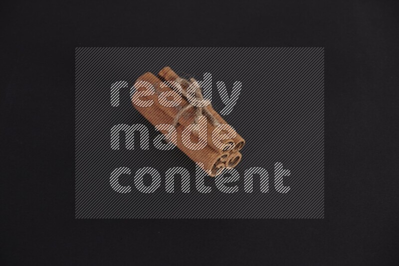 4 أعواد من القرفة مربوطة علي خلفية سوداء