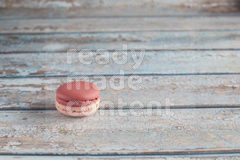 45º Shot of Pink Litchi Raspberry macaron on light blue wooden background