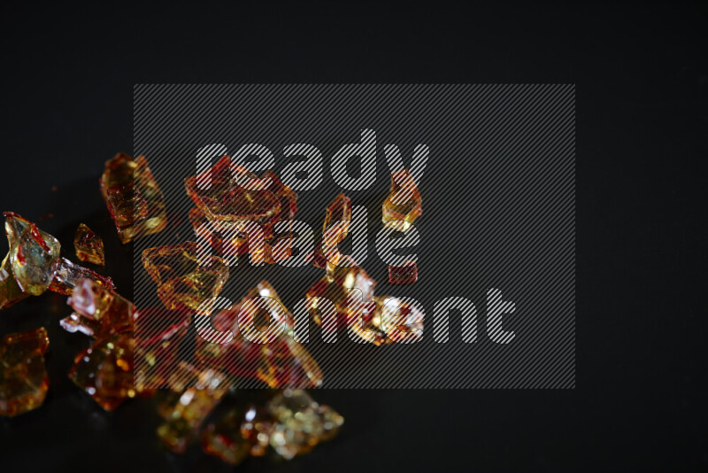 Transparent orange fragments of glass scattered on a black background