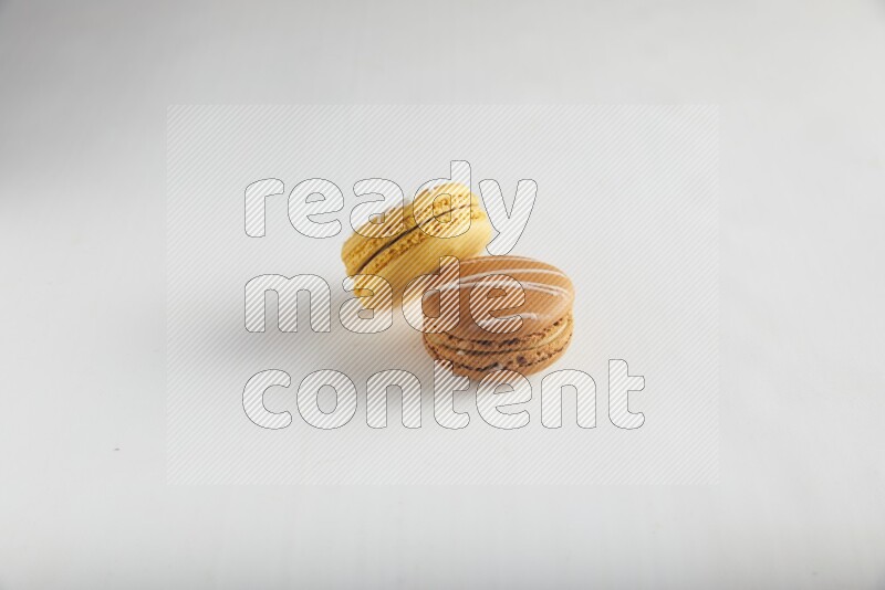 45º Shot of of two assorted Brown Irish Cream, and Yellow Piña Colada macarons on white background