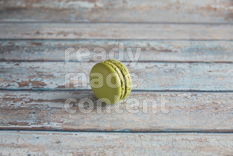 45º Shot of Green Pistachio macaron on light blue wooden background