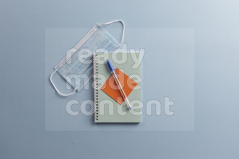 A blue notebook with different school supplies on blue background