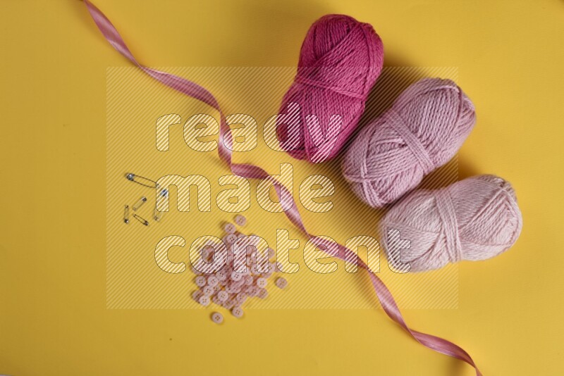 A pink collection of sewing and tailoring tools arranged on a yellow background