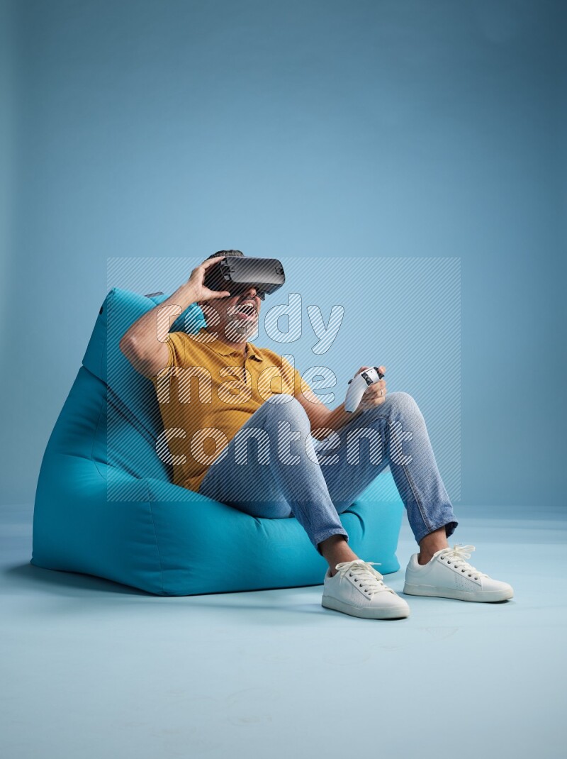 A man sitting on a blue beanbag and gaming with VR